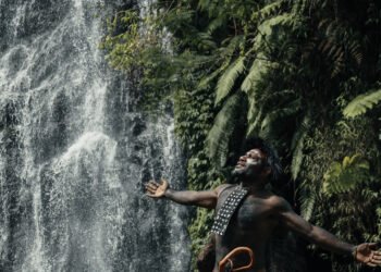 Koteka tradisional suku Papua dengan latar pegunungan Jayawijaya