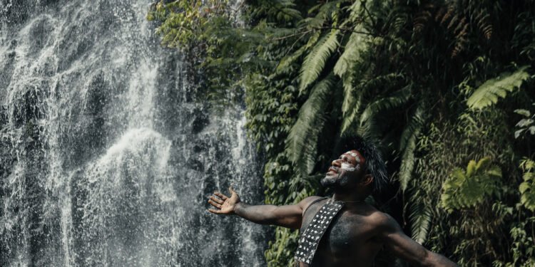 Koteka tradisional suku Papua dengan latar pegunungan Jayawijaya